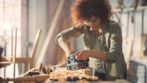 Female carpenter using electric belt sander