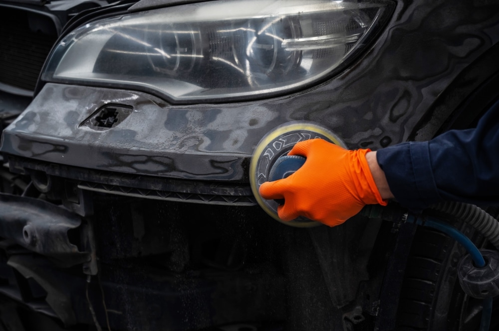 Car mechanic sanding a car